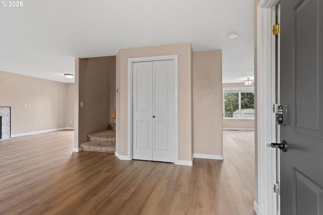 interior space with stairs, a textured ceiling, wood finished floors, and baseboards