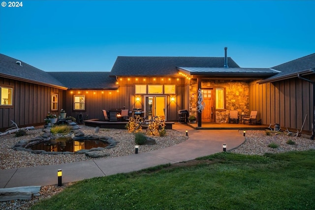 back house at dusk with a patio area and a lawn