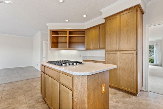 kitchen featuring ornamental molding, stainless steel gas stovetop, a kitchen island, and light carpet