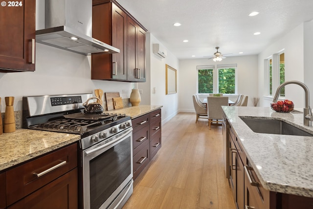 kitchen featuring light stone countertops, stainless steel range with gas cooktop, and wall chimney range hood