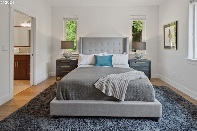 bedroom with hardwood / wood-style flooring and ensuite bath