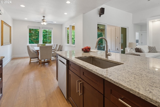 kitchen with sink, light stone counters, light hardwood / wood-style floors, and stainless steel dishwasher