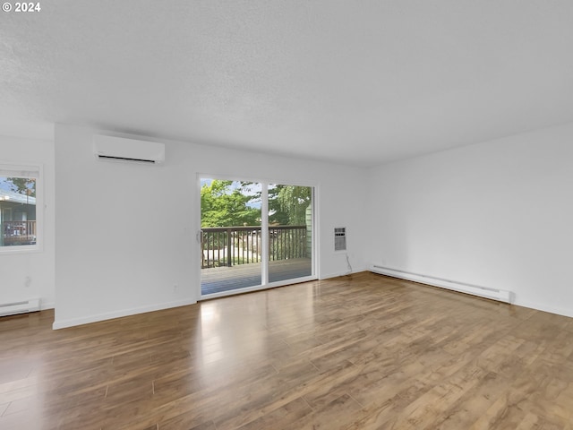 empty room featuring hardwood / wood-style flooring, a baseboard radiator, an AC wall unit, and a textured ceiling