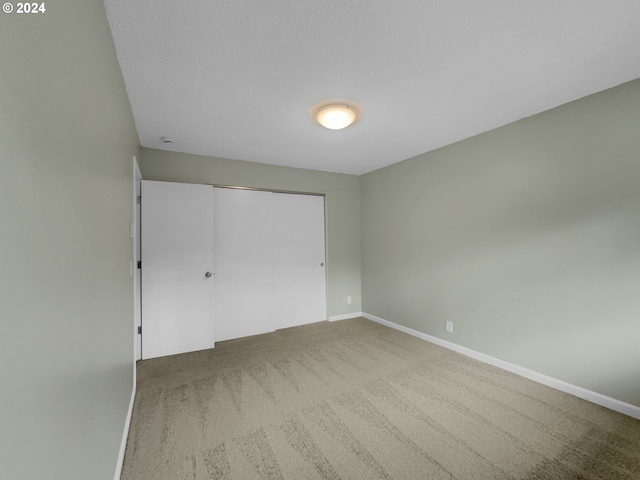 unfurnished bedroom featuring a closet, carpet, and a textured ceiling