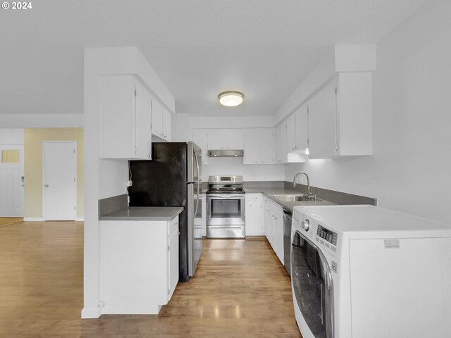 kitchen featuring sink, appliances with stainless steel finishes, light hardwood / wood-style floors, white cabinets, and washer / dryer