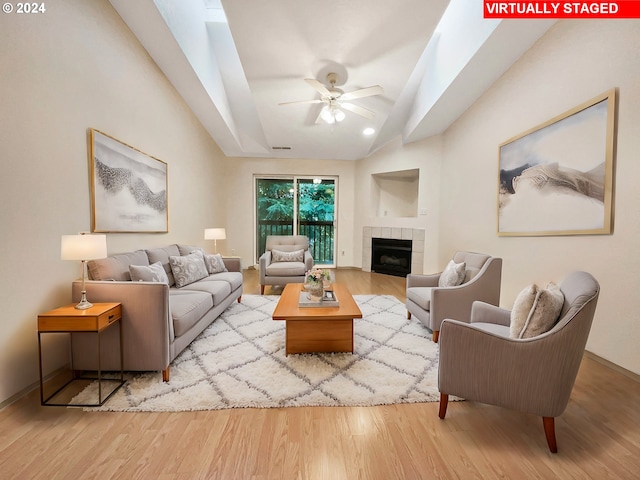 living room with lofted ceiling, a tile fireplace, light hardwood / wood-style floors, and ceiling fan