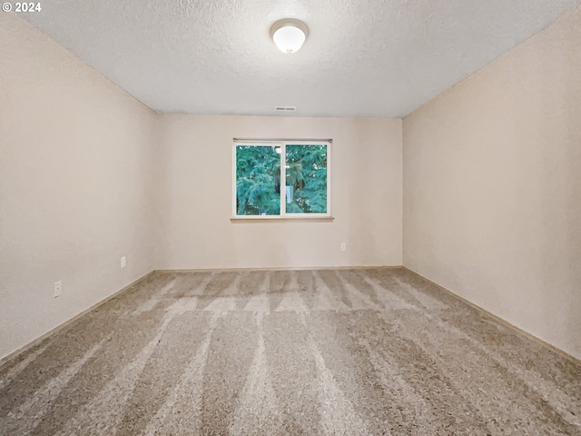 carpeted empty room featuring a textured ceiling