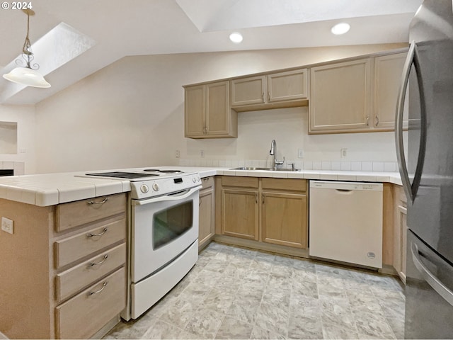 kitchen with tile counters, sink, vaulted ceiling with skylight, pendant lighting, and white appliances