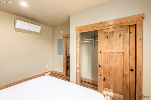 unfurnished bedroom with dark hardwood / wood-style flooring, a closet, and a wall mounted AC