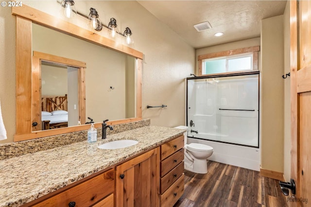 full bathroom featuring vanity, hardwood / wood-style floors, enclosed tub / shower combo, toilet, and a textured ceiling