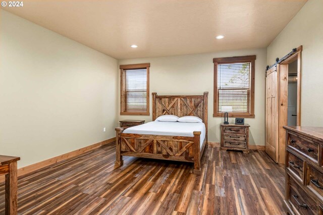 bedroom with dark hardwood / wood-style flooring and a barn door