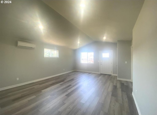 empty room featuring vaulted ceiling, dark hardwood / wood-style flooring, and a wall mounted AC