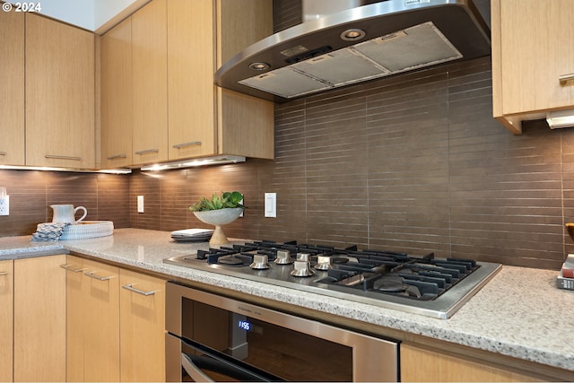 kitchen with stainless steel appliances, wall chimney exhaust hood, backsplash, and light brown cabinets