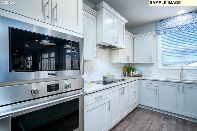 kitchen with stainless steel appliances, sink, dark hardwood / wood-style floors, backsplash, and white cabinetry