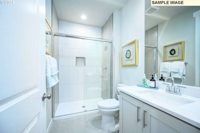 bathroom featuring toilet, tile patterned floors, vanity, and a shower with door