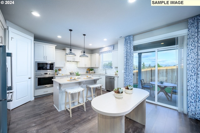 kitchen featuring white cabinetry, decorative light fixtures, appliances with stainless steel finishes, and a center island