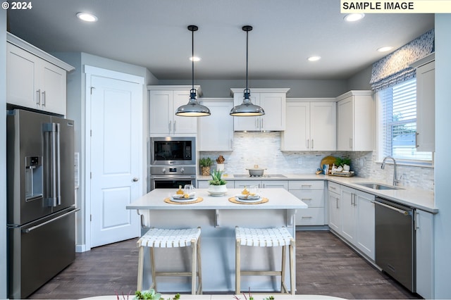 kitchen with stainless steel appliances, white cabinetry, a kitchen breakfast bar, dark wood-type flooring, and pendant lighting