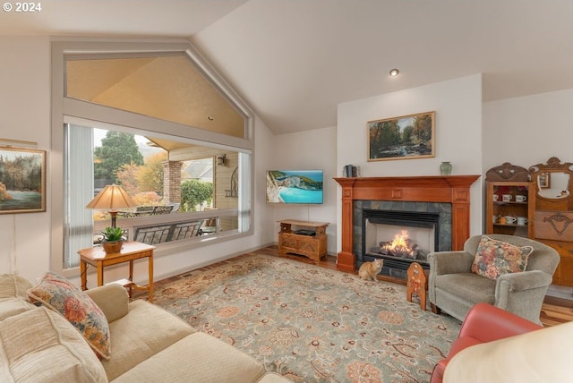 living room with lofted ceiling, light hardwood / wood-style flooring, and a tiled fireplace