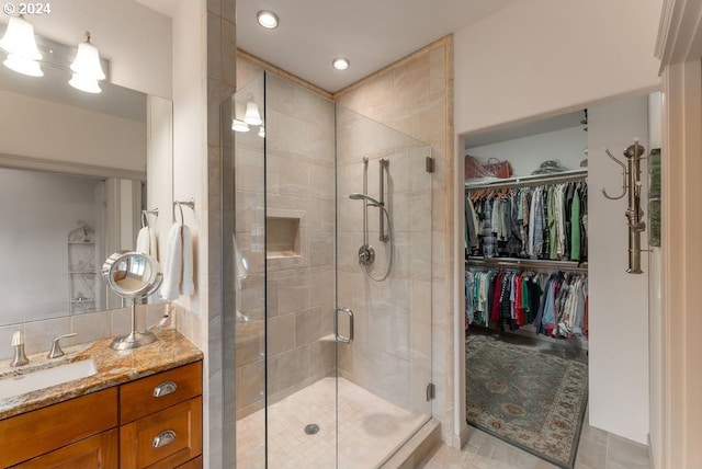 bathroom with tile patterned floors, a shower with door, and vanity