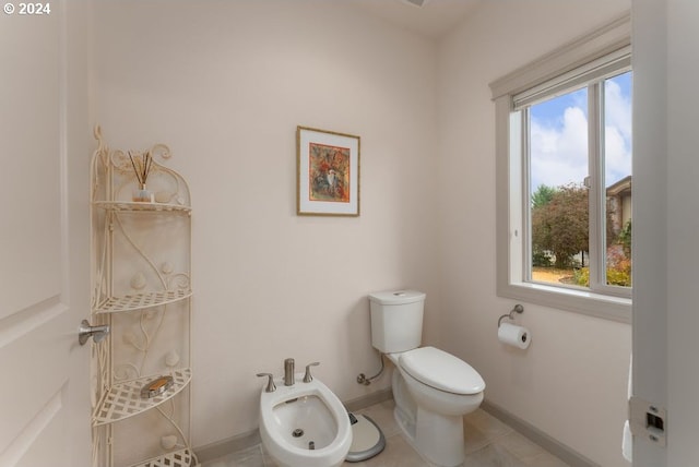 bathroom featuring tile patterned flooring, toilet, and a bidet