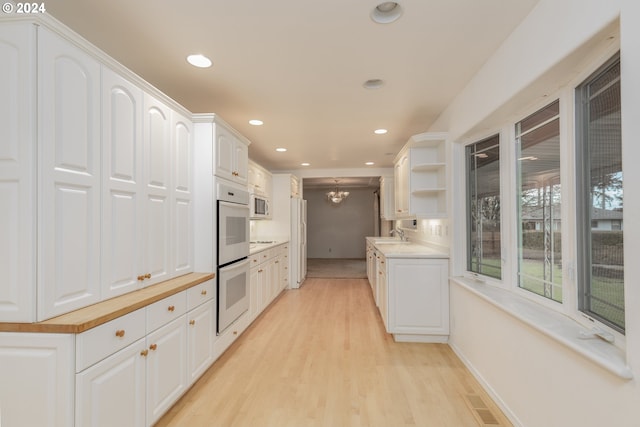 kitchen featuring white appliances, light hardwood / wood-style floors, white cabinetry, and sink