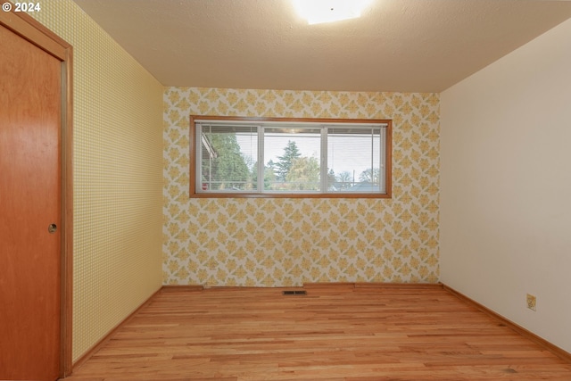 unfurnished room featuring light hardwood / wood-style floors and a textured ceiling