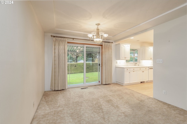 spare room featuring light colored carpet, sink, and a chandelier