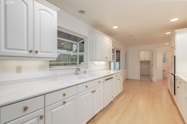 kitchen featuring white cabinets, light hardwood / wood-style flooring, dishwasher, and sink