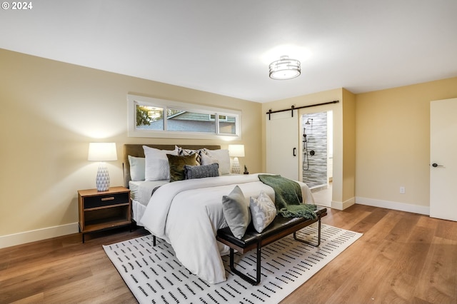 bedroom featuring a barn door and light hardwood / wood-style floors