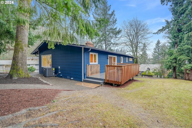 rear view of house featuring a lawn, central AC unit, and a wooden deck