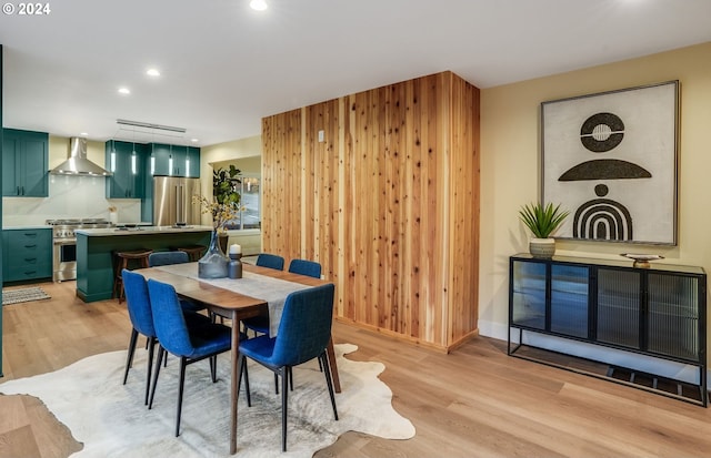 dining room with wood walls and light hardwood / wood-style floors