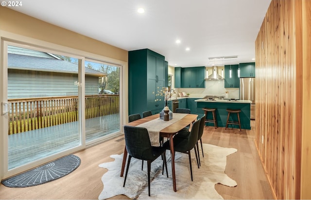 dining area featuring sink, light wood-type flooring, and wood walls