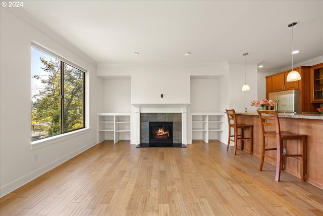 living room featuring a wealth of natural light, a fireplace, light hardwood / wood-style flooring, and ornamental molding