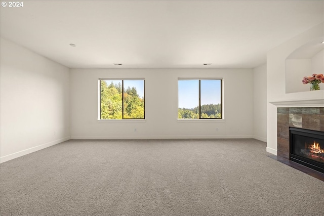 unfurnished living room featuring a tile fireplace and carpet