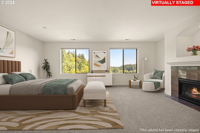 bedroom with a tiled fireplace and carpet