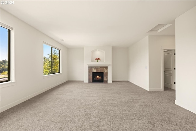 unfurnished living room featuring a tiled fireplace and light colored carpet