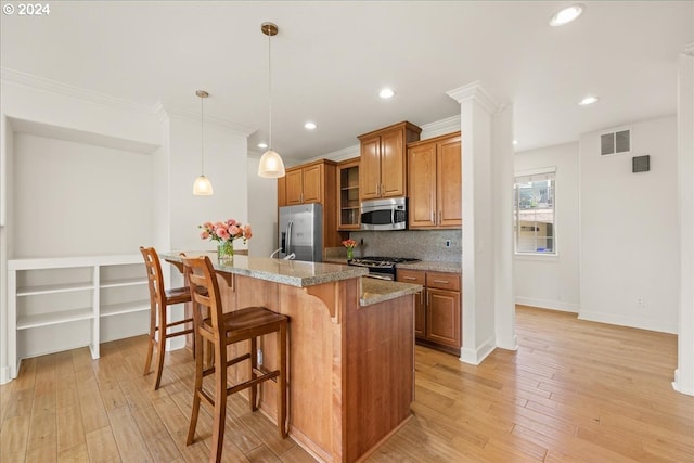 kitchen with light stone countertops, appliances with stainless steel finishes, tasteful backsplash, a breakfast bar, and a kitchen island with sink