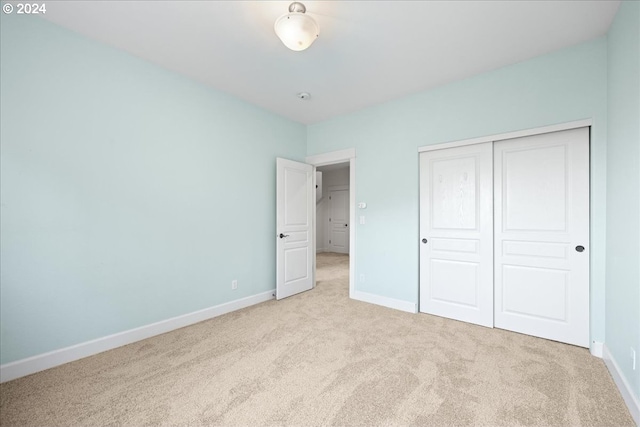 unfurnished bedroom featuring light colored carpet and a closet