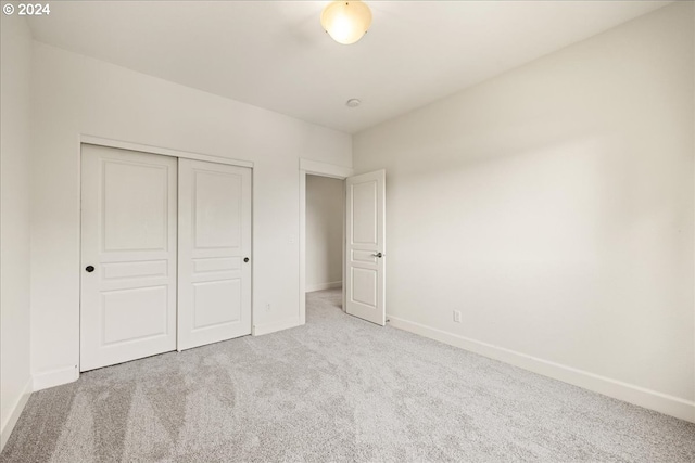 unfurnished bedroom featuring a closet and light colored carpet