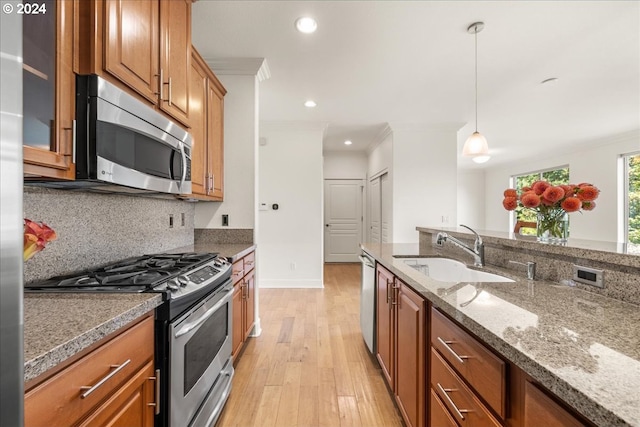 kitchen featuring decorative light fixtures, stainless steel appliances, crown molding, and sink