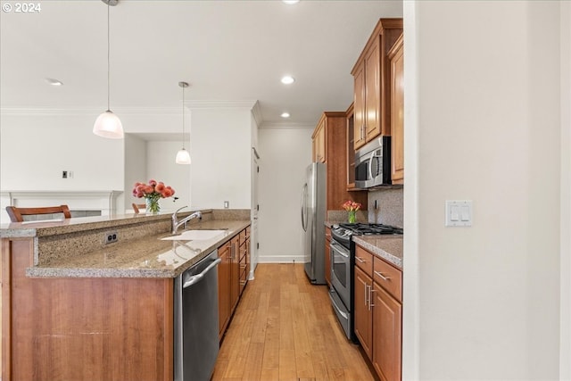 kitchen with pendant lighting, sink, light hardwood / wood-style floors, light stone counters, and stainless steel appliances