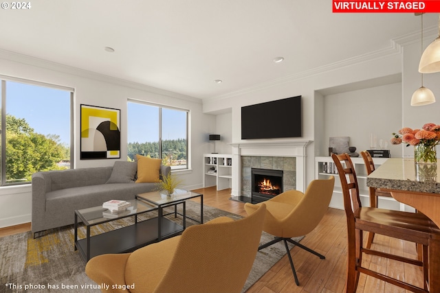 living room with a tile fireplace, hardwood / wood-style flooring, and ornamental molding