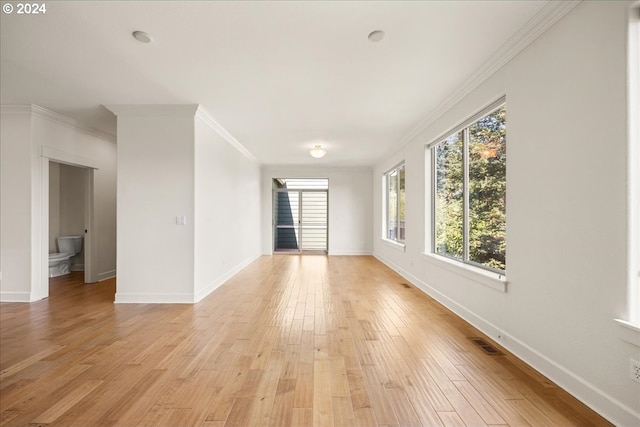 spare room featuring a healthy amount of sunlight, light wood-type flooring, and ornamental molding