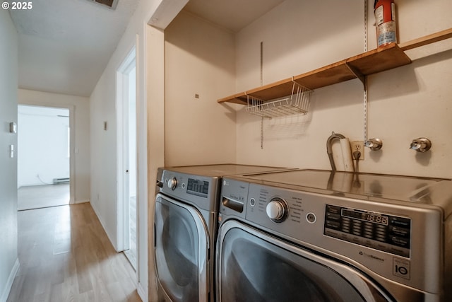 laundry room featuring light hardwood / wood-style flooring, washer and dryer, and a baseboard heating unit