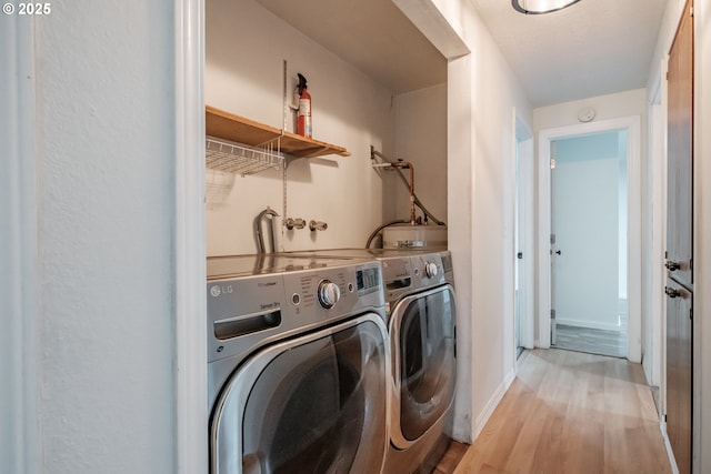 laundry area with light hardwood / wood-style flooring and washing machine and clothes dryer