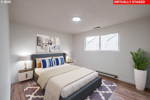 bedroom featuring wood-type flooring and a baseboard heating unit