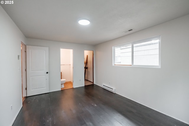 unfurnished bedroom with a spacious closet, a baseboard radiator, dark hardwood / wood-style floors, ensuite bathroom, and a closet