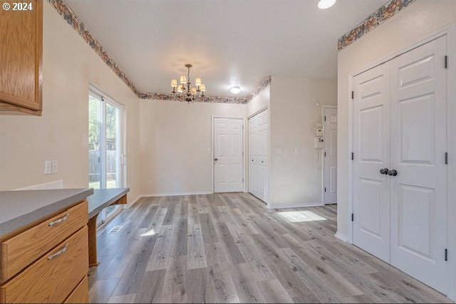 unfurnished dining area with a chandelier and light hardwood / wood-style floors