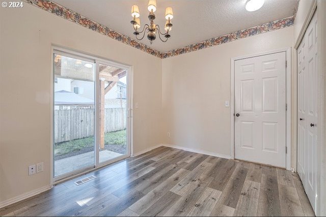 interior space featuring wood-type flooring, a healthy amount of sunlight, and an inviting chandelier