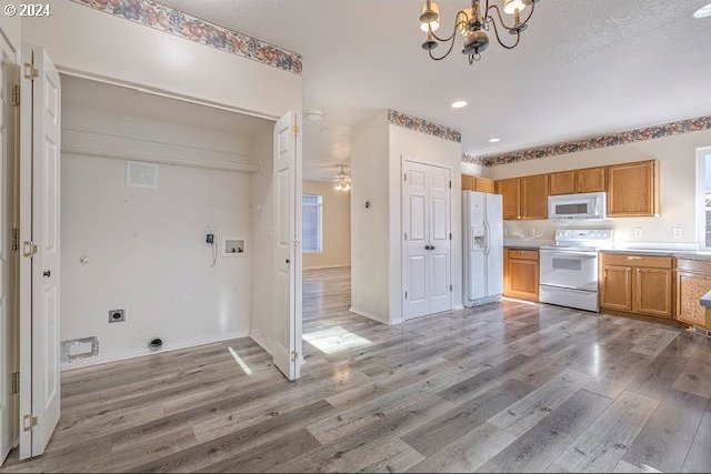 kitchen with light hardwood / wood-style floors, a notable chandelier, and white appliances